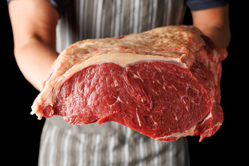 Butcher holding with hands a large piece of beef sirloin steaks