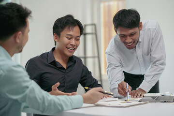 Three young asian entrepreneurs are having fun analyzing a business growth graph in a meeting
