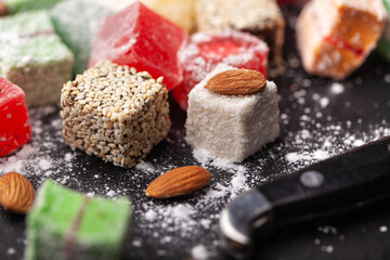 Assortment of Turkish sweets with nuts on a black background. A scattering of Turkish delight