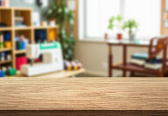 Blur Sunny Fashion Design Studio and wooden table top. We See, Hanging Clothes, Sewing Machine and Various Sewing Related Items on the Table, Mannequins Standing, Colorful Fabrics.