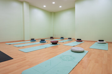 Empty yoga studio with yoga mats and pillows ready for class