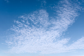 A beautiful, clear blue sky with wispy white clouds, gently rolling across the sky