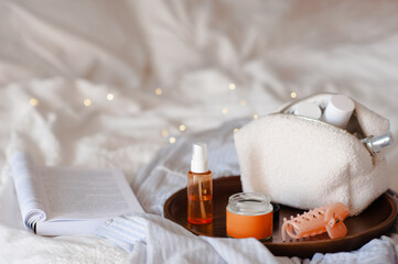 Cosmetic bag with face cream and lotion on tray in bed closeup. Skin care.