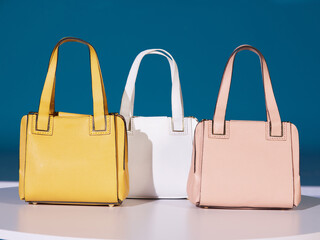 Women's bags made of leather. In 3 different colors, luxury, bags on a white background and a blue background, in the studio. Yellow, white and pink bags