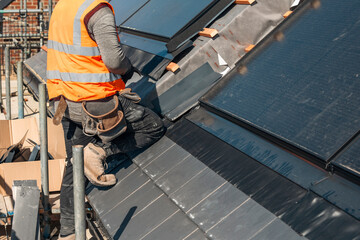 Skilled worker installing solar panels on a modern rooftop in bright sunlight