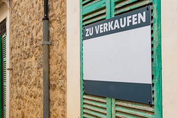 For sale sign written in German on the facade of a historic building on the island of Mallorca