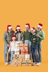 Big family in Santa hats with Christmas presents on yellow background