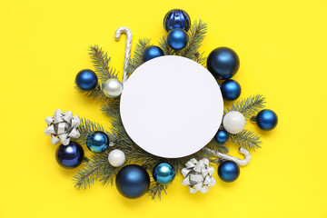 Blank card, Christmas balls, candy canes and fir branches on yellow background