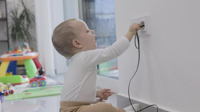 Baby is playing with an electrical outlet, putting himself in danger