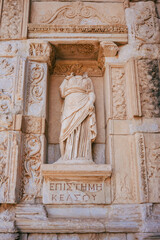 A detailed photo of an ancient marble statue without a head, set within a carved stone niche. This image is ideal for themes related to ancient architecture, archaeology, and historical monuments.