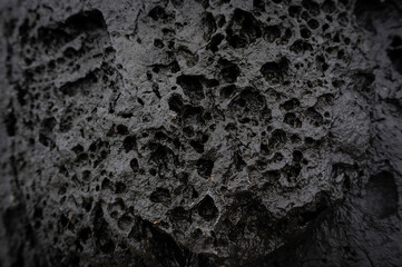 Black background grey lava stone with erosion holes caused by wind, water and weather. Backdrop...