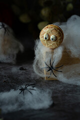 Funny spooky french macarons beige with eyes on dark background with spiders and spider net