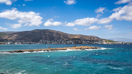 View from a near by hill to the small town by the sea of Porto Rafti at Attica-Greece. Nice blue sky and clouds at the background.