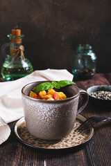 Bread pudding with egg, pepper and basil in a cup on the table vertical view