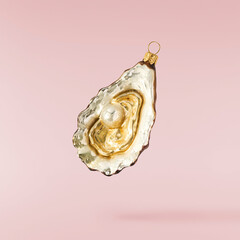 Christmas holliday image, Christmas bauble in shape of a oyster falling in the air isolated on pink...