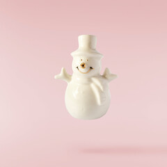 Christmas holliday image, Christmas bauble in shape of a snowman falling in the air isolated on pink background