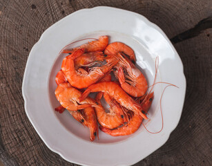 Raw shrimps in porcelain plate on wooden table