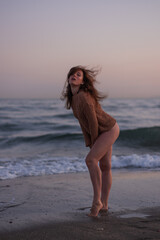 Beautiful girl posing against the backdrop of a sea beach on a warm summer evening. Beautiful bokeh and sea waves in the background