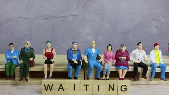 A group of people doll miniatures sitting on a palette, waiting in front of a concrete wall. Waiting for luck love train station Better future Life opportunities procrastinating