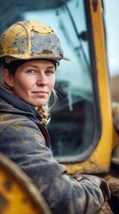 Portrait of a determined female construction worker wearing a hard hat at a worksite during the day with heavy machinery in the background