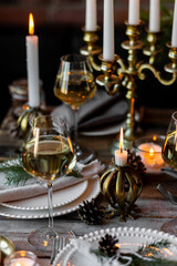 Rustic Scandinavian style zero waste eco-friendly dinner table decor for Christmas or new year family celebration. Wooden table, natural elements like pine cones, fir tree branches, candles