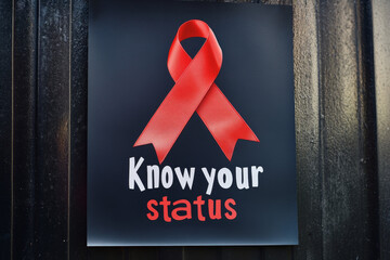Know your status poster with red ribbon on black background for health awareness campaign. World AIDS Day