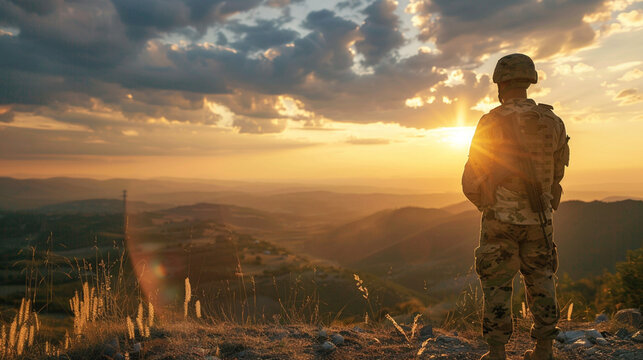 War and peace concept. Soldier in a helmet looks at the sunset. A man in a military uniform stands on a mountain and looks into the distance at a field. War, peace and freedom concept