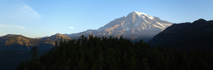 Aerial view of Mount Rainier at sunrise with forested mountains in Washington State, USA