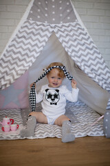 Adorable beautiful happy smiling ginger-haired toddler little girl is playing with her toys sitting in a teepee wigwam © Tina