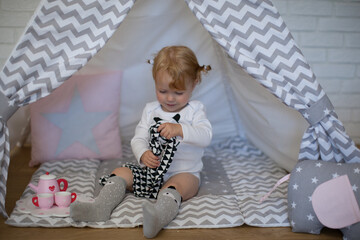 Adorable beautiful happy smiling ginger-haired toddler little girl is playing with her toys sitting...