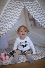 Adorable beautiful happy smiling ginger-haired toddler little girl is playing with her toys sitting...
