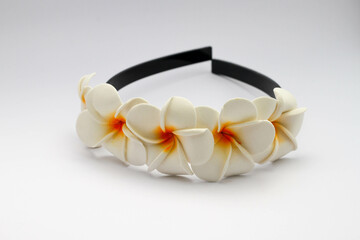 Black plastic headband decorated with white frangipani flower ornaments, isolated on white background. Accessories for girls.