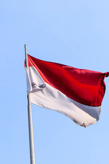 Red and white Indonesian flag waving on top a pole.