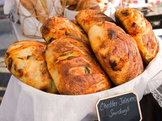 Loaves of freshly baked artisan cheddar jalapeno pepper sourdough bread for sale at an outdoor. market