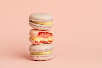 stack of macaroons, one of which is bitten. tasty almond dessert on bright pink background, funny abstraction on taste theme