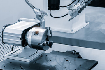 A machine with a three pronged tool is sitting on a table. The machine is surrounded by other tools and parts. Concept of precision and technical expertise