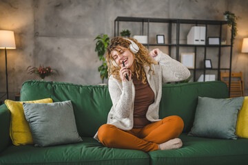 Obraz premium One woman with headphones at home listen music online happy smile sing