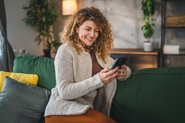 One woman with curly hair at home use mobile phone smartphone sms texting or browse internet
