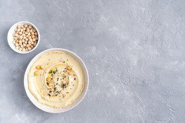 Hummus with olive oil in a gray ceramic plate. Toast and breadsticks for snacks. Top view, on a gray background.