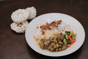 Gulai Kambing or Lamb Curry with rice on a white palte and krupuk, Traditional Javanese mutton curry soup.