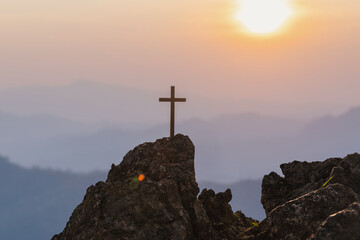 Silhouettes of crucifix symbol on top mountain with bright sunbeam on the colorful sky background