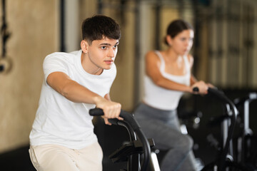 Young athletic man working out on exercise bike in gym