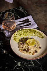 Mushroom risotto with pink wine. Luxurious and expensive gourmet meal prepared on a black marble table, served with a glass of wine