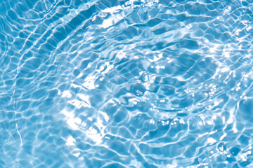 Blue water with ripples on the surface. Defocus blurred transparent blue colored clear calm water surface texture with splashes and bubbles. Water waves with shining pattern texture background.
