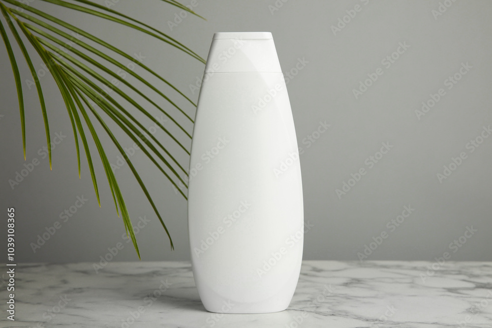 Wall mural Bottle of shampoo on white marble table against grey background