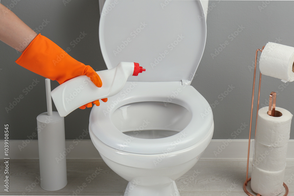 Poster Woman cleaning toilet with detergent in bathroom, closeup