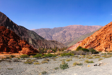 Lush green valleys contrasting with the arid beauty of the Seven Colors Hill, Purmamarca, Jujuy, Argentina.
