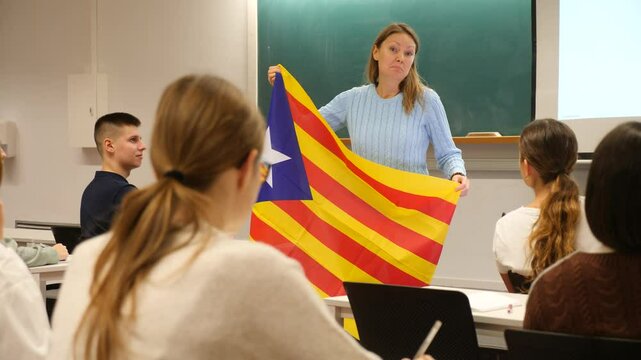 Confident young female professor shows students estalada flag of Catalonia. High quality 4k footage