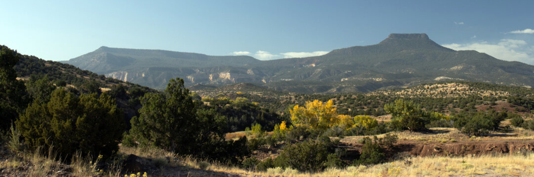 Ultra-wide panoramic view of Cerro Pedernal, a distinctive northern New Mexico landmark, from the edge of Ca&ntilde;ones Creek