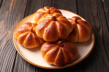 Tasty pumpkin shaped buns on wooden table, closeup